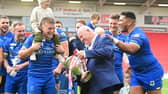 Dons chief executive Carl Hall celebrates promotion with the players.