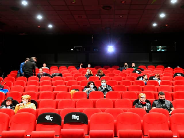 People wearing protective face masks await the beginning of a movie.