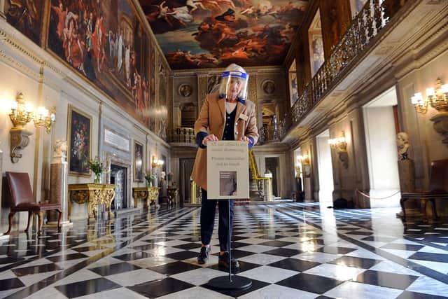 Chatsworth House reopening to visitors. Lizzie Ross visitor welcome supervisor placing new signs for social distancing in the Painted Hall in July.