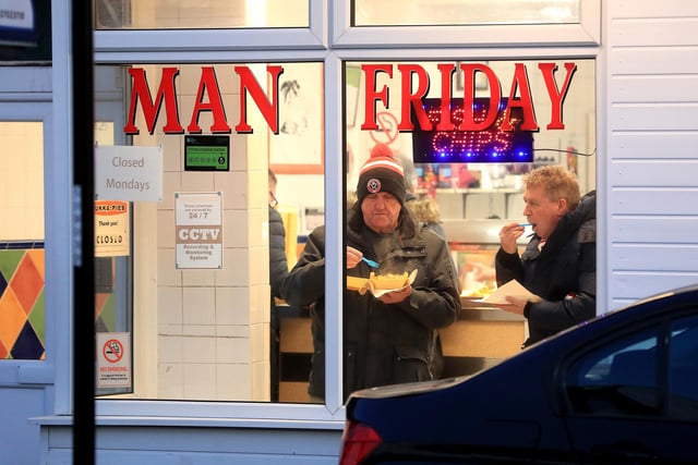 Sheffield United fans stop at a fish and chip shop near the stadium before the game