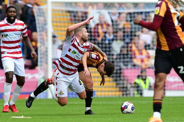Doncaster's Adam Clayton is brought down by Bradford's skipper Richie Smallwood.