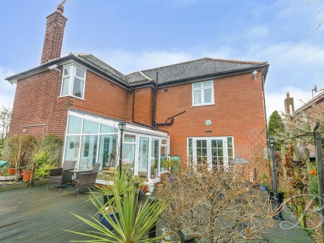 A view from the back of the house, showing the decked patio area, with seating, outside the conservatory.
