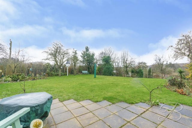The house stands on a spacious and well-established plot. This image of the back garden, with its maintained lawn and surrounding trees and shrubs, confirms that.