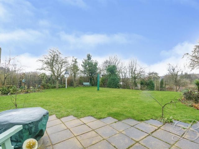 The house stands on a spacious and well-established plot. This image of the back garden, with its maintained lawn and surrounding trees and shrubs, confirms that.