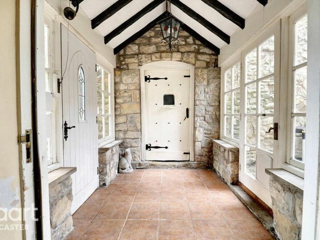 A walkway with beamed ceiling and exposed stonework.