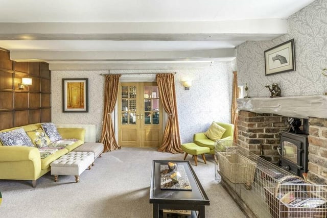 A cosy beamed reception room with brick fireplace and stove.