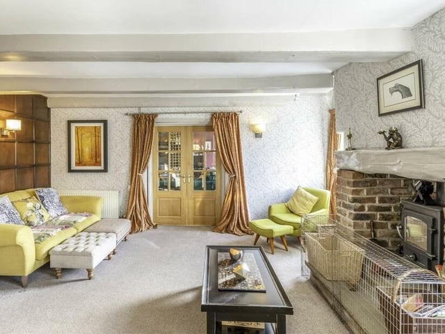 A cosy beamed reception room with brick fireplace and stove.