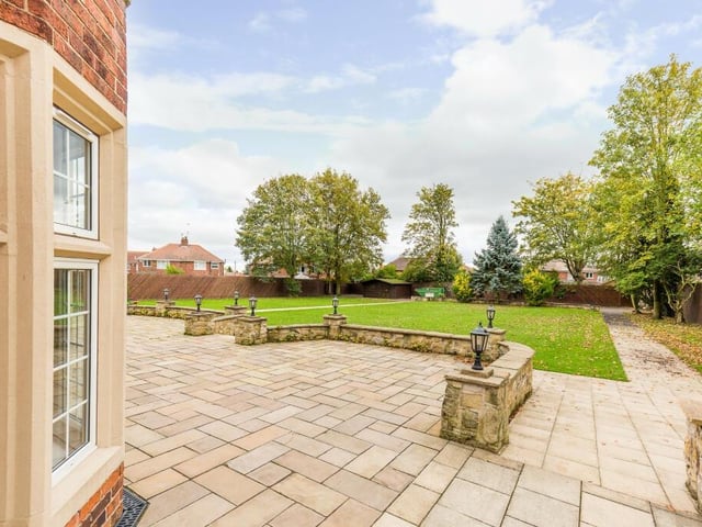 A stunning rear garden with lawns, terraces and pathways, one leading to a log cabin.