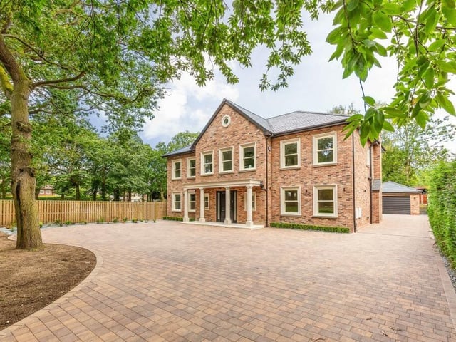 Electric gates open to the wide driveway and impressive frontage of the six-bedroom home.