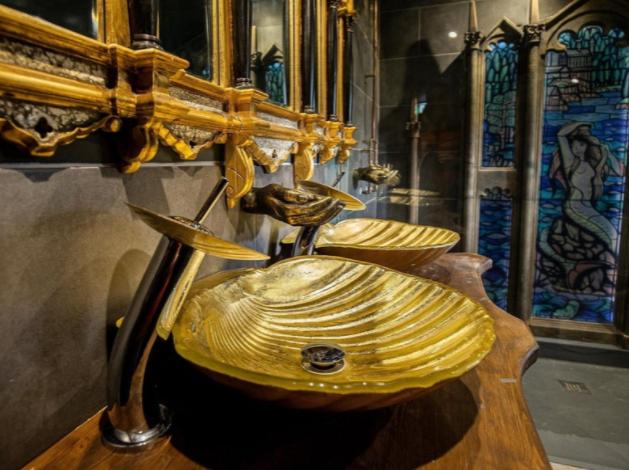 The opulent bathroom features ornate Gothic style mirrors and golden hand basins in the shape of giant shells.