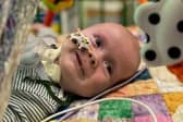 Theo smiles whilst lying underneath a colourful mobile.