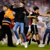 A Nottingham Forest player escorts Sheffield United's Morgan Gibbs-White off the pitch as fans invade the playing surface at the City Ground: Mike Egerton/PA Wire.