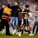 A Nottingham Forest player escorts Sheffield United's Morgan Gibbs-White off the pitch as fans invade the playing surface at the City Ground: Mike Egerton/PA Wire.