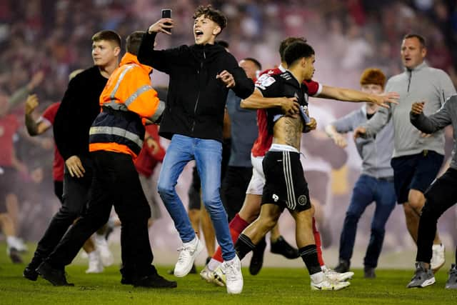 A Nottingham Forest player escorts Sheffield United's Morgan Gibbs-White off the pitch as fans invade the playing surface at the City Ground: Mike Egerton/PA Wire.