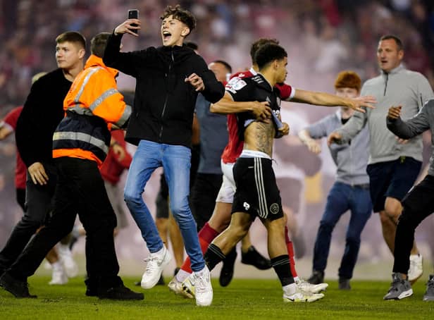 A Nottingham Forest player escorts Sheffield United's Morgan Gibbs-White off the pitch as fans invade the playing surface at the City Ground: Mike Egerton/PA Wire.