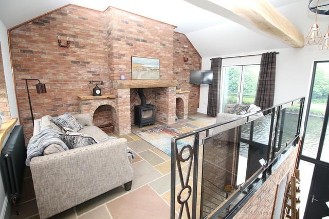 Stylish waterside living - a room with exposed brick wall and warming stove.