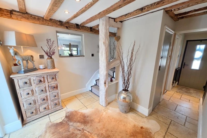 A welcoming netrance hall has a tiled floor and original wooden beams to the seiling, with a feature staircase leading up.