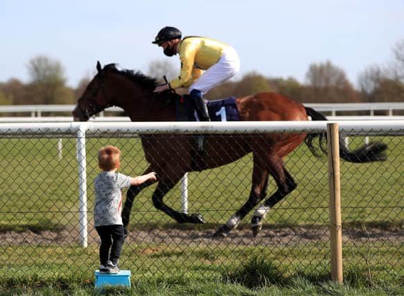 A young spectator watches Sam James riding Rum Runner go past in the Sky Sports Racing Virgin 535 Handicap at Doncaster Racecourse on April 23. Photo: Mike Egerton - Pool / Getty Images