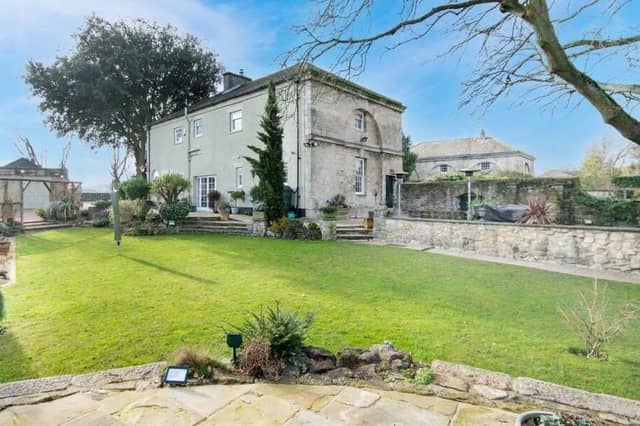An exterior view of the detached home from its lawned gardens.