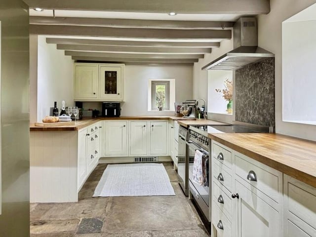 The modern kitchen with original beams to the ceiling and a flagstone floor.
