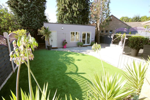 The landscaped back garden features a partially paved and composite decked terrace, a low maintenance artificial lawn, recessed patio lights and the purpose-built outdoor building.