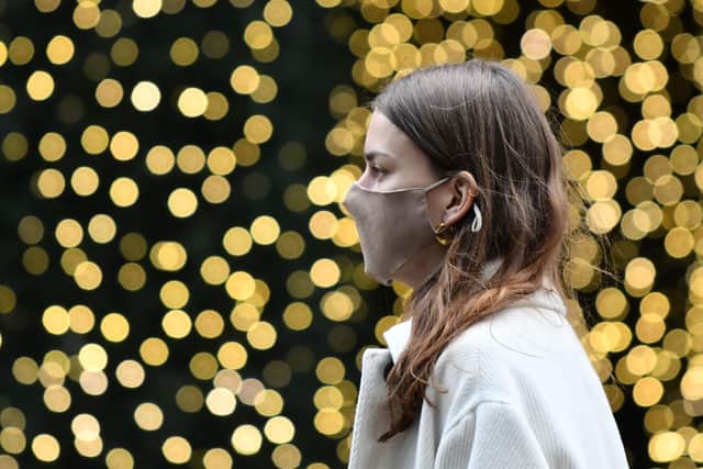 A pedestrian wearing a face mask walks past a Christmas light display (Photo by JUSTIN TALLIS/AFP via Getty Images)