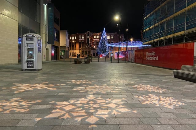 Snowflakes are projected onto the pavement.