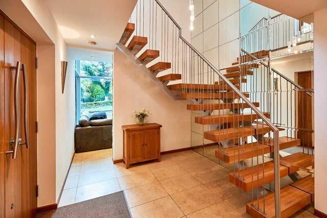 A striking oak staircase is suspended by a bespoke chrome balustrade.