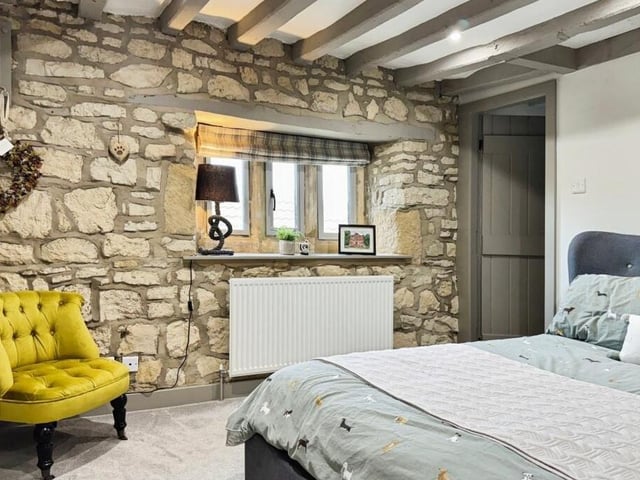 Another bedroom with exposed stonework and ceiling beams.