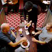 Customers are pictured being served a meal at a Wetherspoon pub. The chain has launched a deal called Stay Out to Help Out. Picture: Tolga Akmen/AFP via Getty Images.