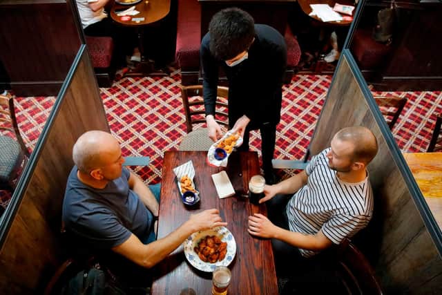 Customers are pictured being served a meal at a Wetherspoon pub. The chain has launched a deal called Stay Out to Help Out. Picture: Tolga Akmen/AFP via Getty Images.