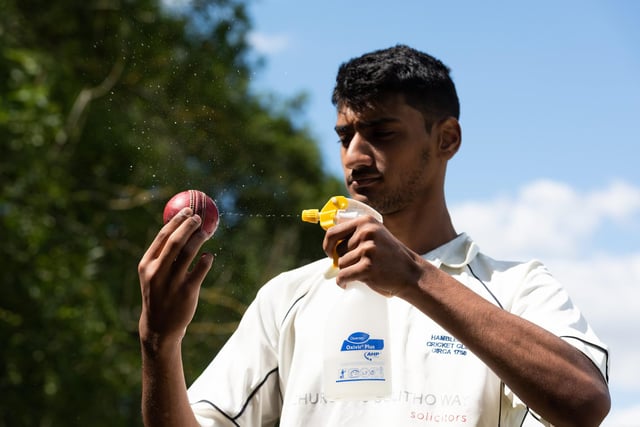 Shahryar Kahn of Hambledon Cricket Club disinfects the ball during the interval as they return to action at Ridge Meadow. Pic: Jordan Pettitt/Solent News & Photo Agency