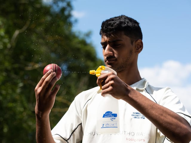 Shahryar Kahn of Hambledon Cricket Club disinfects the ball during the interval as they return to action at Ridge Meadow. Pic: Jordan Pettitt/Solent News & Photo Agency
