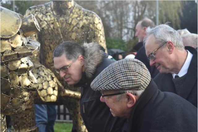 Visitors inspect the new statue closely.