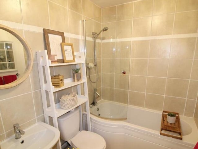 The bathroom has a shaped bath and overhead shower.