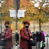 A woman is reflected in a window as she leaves a shop in central Sheffield (Photo by OLI SCARFF/AFP via Getty Images)