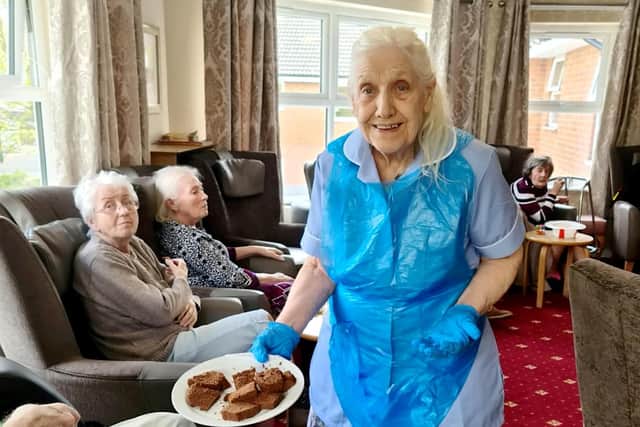 Maureen Townend handing out the cake. An 83-year-old care home resident has volunteered to work as a care assistant at her own home to help out staff. See SWNS story SWLEcarer. Maureen Townend expressed to staff at Flower Park Care Home in Doncaster, South Yorkshire, where she is a resident, how much she would like to be a care assistant. After haggling with carers, the care home finally allowed the caring OAP to work as a volunteer amongst her friends and other residents.