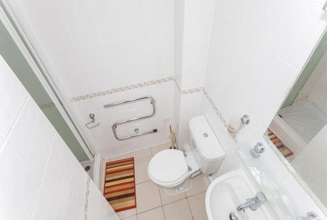 Contemporary and modern shower room with tiling to all walls and floor in white with an attractive mosaic accent.