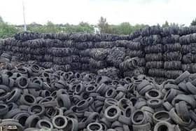 The photograph shows large piles of waste tyres at the illegal site.