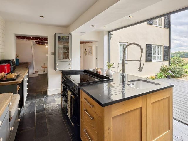 The modern kitchen has bi-fold doors to outdoor decking with exceptional views.