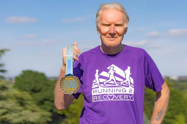 Jim proudly holding the medal he collected for completing 100 marathons