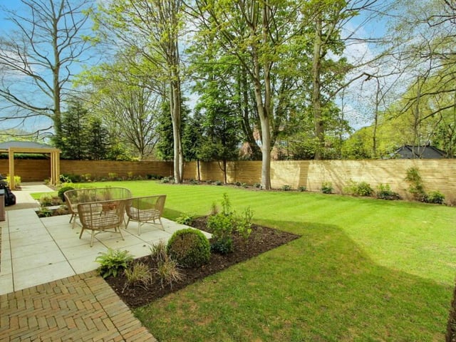 Tranquil gardens with seating areas and a backdrop of trees.