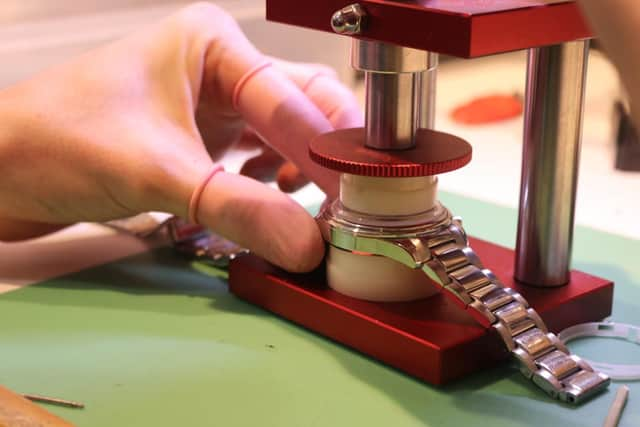 Adam Jones, repairing watch in shop.