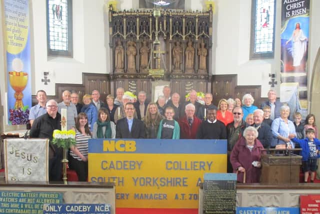Behind former Cadeby pit signs are Father Desmond Edozie, Parish Priest of St Albans Church, Denaby Main, Rev Martijn Mugge, Vicar of St Peters Parish Church, Conisbrough, Cllr Nigel Ball, Cabinet Member for Public Health, Leisure and Culture, Cllr Lani Ball, Cllr Ian Pearson, Jeff Lovell, Chair of Cadeby Main Colliery Memorial Group, Ruth Carrington, Pit Sense Project Officer, Louise Jackson, Community & Skills Coach at the Coalfields Regeneration Trust, former Cadeby Main miners, members of the community and parishioners from St Albans Church