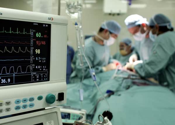 Surgeons carry out an operation to remove a tumour from a patient at an NHS hospital.