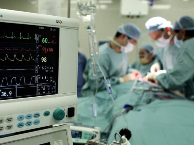 Surgeons carry out an operation to remove a tumour from a patient at an NHS hospital.