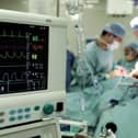Surgeons carry out an operation to remove a tumour from a patient at an NHS hospital.