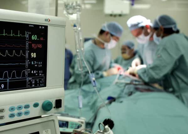Surgeons carry out an operation to remove a tumour from a patient at an NHS hospital.