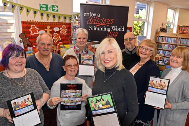 Sprotbrough Library Slimmingworld consultant Amanda Horsman (centre), pictured with members l-r Louise Morton, Jim Breslin, Carmel Proctor, Cheryl Jessop, Jason Horsman, Lyn Robinson and Maureen O'Brien, holding copies of the calendar they have produced to raise money for charity. Picture: Marie Caley NDFP-04-12-18-SlimmingGroupCalendar-1