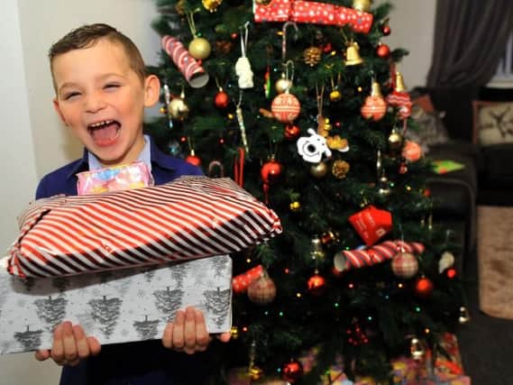 Jacob Pool 5 from Seacroft, Leeds , with some Christmas presents by his Christmas tree.